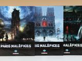 trois livres posés sur une table, avec une tour horloge en arrière-plan
