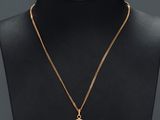 un collier plaqué or avec un pendentif en forme d'oiseau autour du cou d'un mannequin