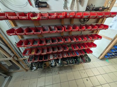 de nombreux bacs rouges contenant des outils, posés sur une étagère dans un garage