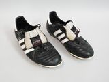 une paire de chaussures de foot noires et blanches posées sur une surface blanche