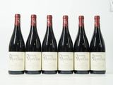 six bouteilles de vin sont alignées sur une surface blanche
