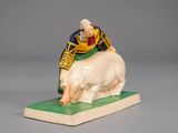 figurine of a man riding a white horse on a green base