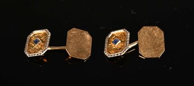 three pairs of gold and sapphire cufflinks on a black surface