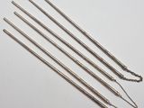 un ensemble de cinq aiguilles en acier inoxydable munies de chaînes, posées sur un fond blanc