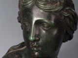 bronze statue of a woman with curly hair and a flower in her hair