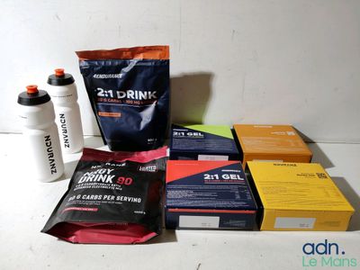 Plusieurs sachets de boisson protéinée sont posés sur un plan de travail, à côté d'une bouteille d'eau