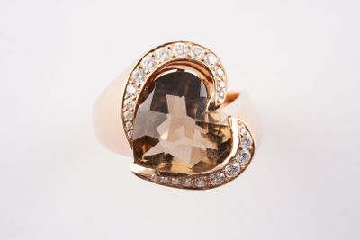 un gros plan d'une bague ornée d'une grosse pierre brune entourée de diamants blancs
