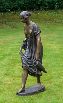 une statue représentant une femme tenant un sac à main dans un champ