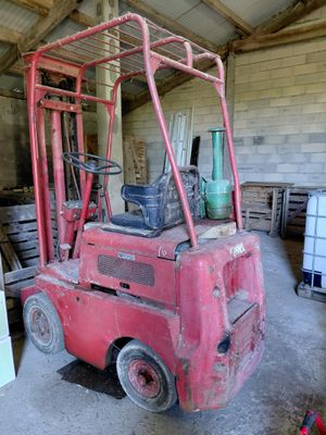un chariot élévateur rouge dans un bâtiment où se trouvent de nombreuses palettes