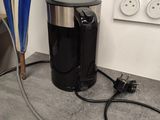 a black coffee maker and a blue umbrella on the floor