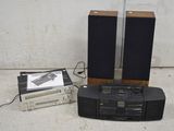 deux haut-parleurs, un lecteur de cassettes et un lecteur de CD posés par terre