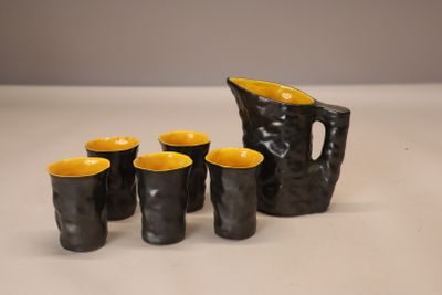 cinq tasses et un pichet posés sur une table