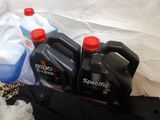 several bottles of motor oil are sitting on a bed next to a pair of pants