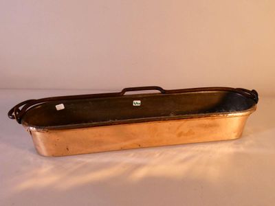 an old copper pan sitting on top of a white table