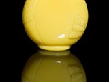un vase jaune avec un couvercle rouge posé sur une surface noire