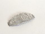 a silver brooch that is laying on a white surface