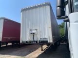 two semi trucks parked next to each other in the dirt