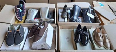 Plusieurs paires de chaussures pour homme sont rangées dans des boîtes posées sur une table
