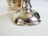 un vase en argent contenant une fleur, posé sur une table