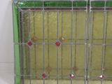 an old stained glass window with a green frame and red and white squares