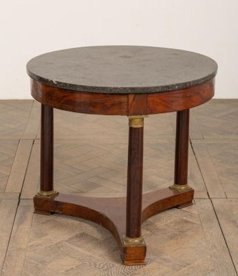 une photo d'une table ronde avec un plateau en marbre posée sur un plancher en bois