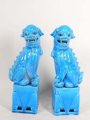 pair of blue foo foo foo statues on pedestals against a white background