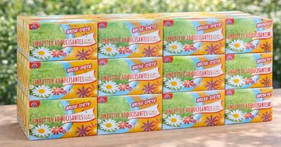 six paquets de papier toilette posés sur une table devant un buisson