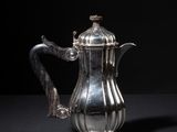 an antique silver coffee pot on a black surface