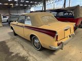 an old yellow car is parked in a garage with other cars
