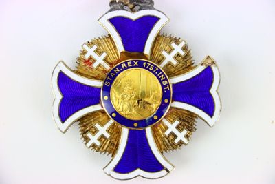 une croix violette et dorée sur laquelle est accrochée une médaille en or