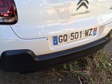 the rear end of a white car parked in a parking lot