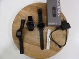 three garmin watches and a charger on a wooden plate