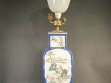 un vase bleu et blanc posé sur une table sur laquelle se trouve une lampe