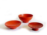 trois bols rouges et un bol posés sur une surface blanche