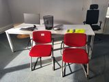 two red chairs sitting at a white table in an office