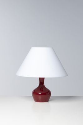 une lampe de table rouge surmontée d'un abat-jour blanc
