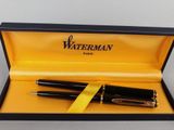 a close up of a pen in a box with a yellow ribbon