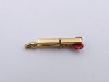 a small gold pen with a red tip on a white surface