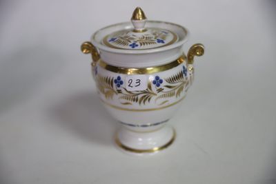 un vase blanc et doré muni d'un couvercle, posé sur une table blanche