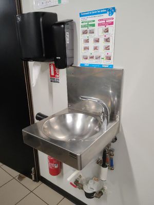 un lavabo en acier inoxydable dans des toilettes publiques dotées d'une porte noire
