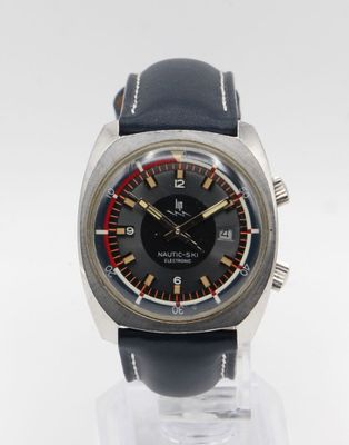 a close up of a watch on a clear stand on a white surface