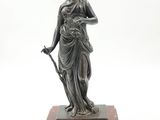 a bronze statue of a woman holding a staff on a marble base