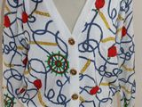 un gros plan sur le torse d'un mannequin portant un cardigan blanc orné de fleurs bleues et rouges