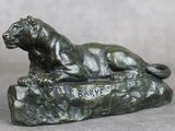 une statue en bronze représentant un lion couché sur un rocher