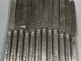 six knives are lined up in a row on a white surface