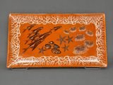 an orange and white plate with fish on it on a gray surface