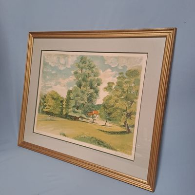 tableau encadré représentant une maison dans un champ, avec des arbres en arrière-plan