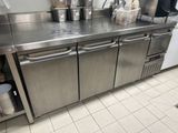 un plan de travail en inox sur lequel sont posés tout un tas de casseroles et de poêles