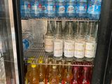 many bottles of water in a cooler on the shelf