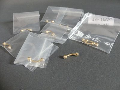 five bags of gold earrings sitting on a table